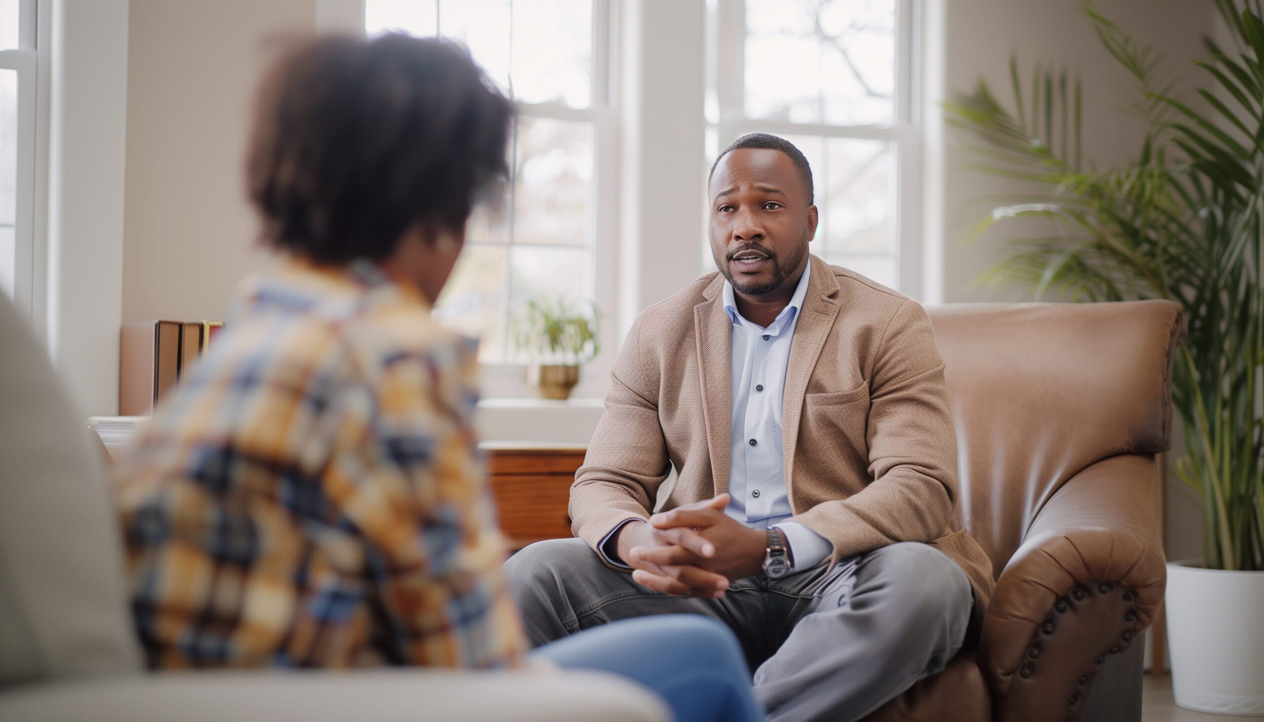 Handsome young african american psychologist man in comfortable armchair during psychological mental supporting patient session
